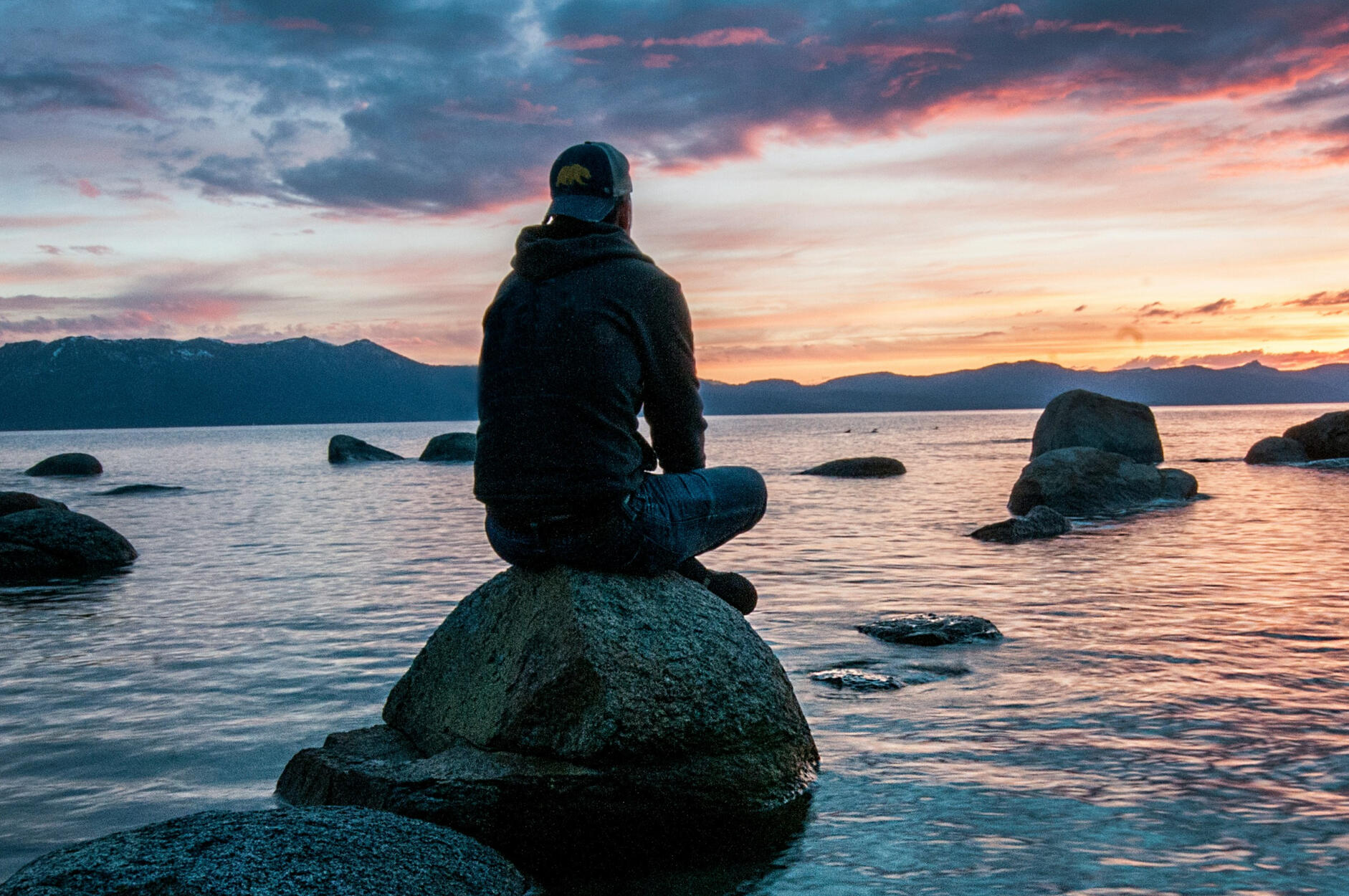 Mindfulness and reflection by the ocean at sunset A person sitting on a rock in the ocean watching the sunset