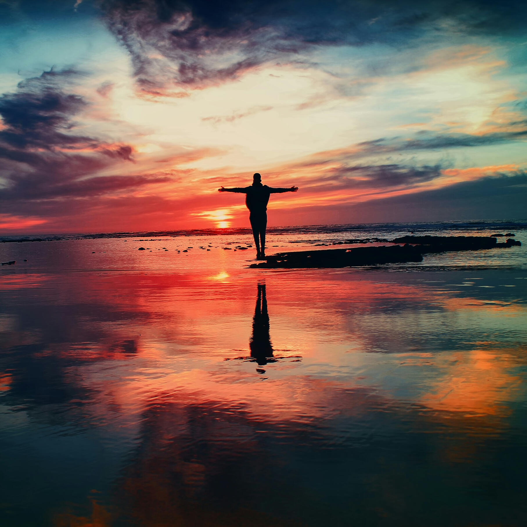 Healing and personal growth by the ocean at sunset Silhouette of a person standing by the ocean at sunset with arms open